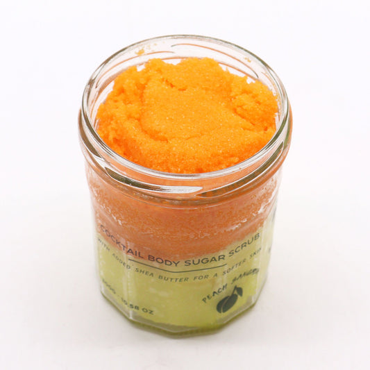 Fragranced sugar body scrub in peach sangria scent by The Bliss Co, showing the 300g jar with peach-colored scrub and floral accents.