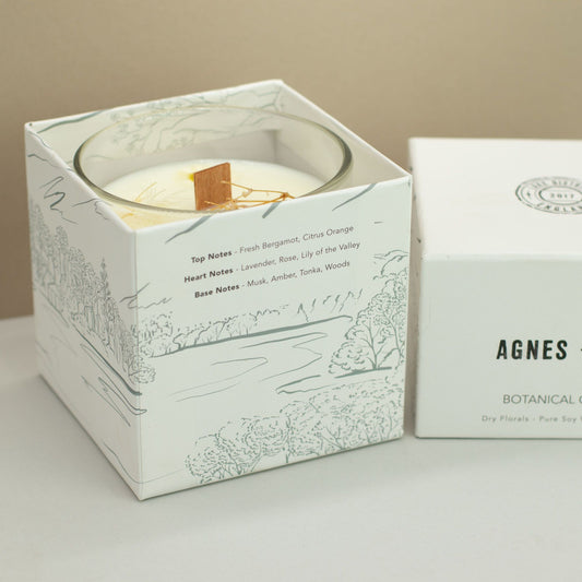 Agnes + Cat Botanical Soy Wax Candle by The Bliss Co in Windermere, featuring a stylish glass jar with a botanical design and lit wick.