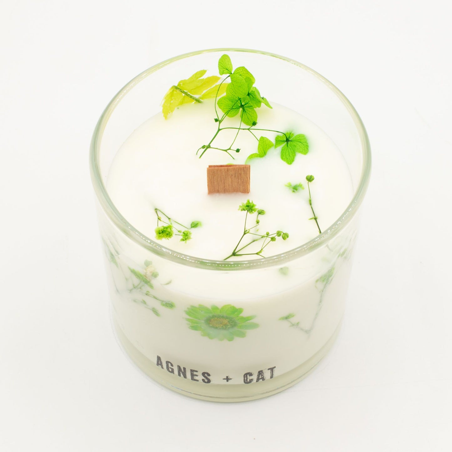Agnes + Cat Fellberry botanical soy wax candle by The Bliss Co, showcasing a white candle with floral design and wooden wick.