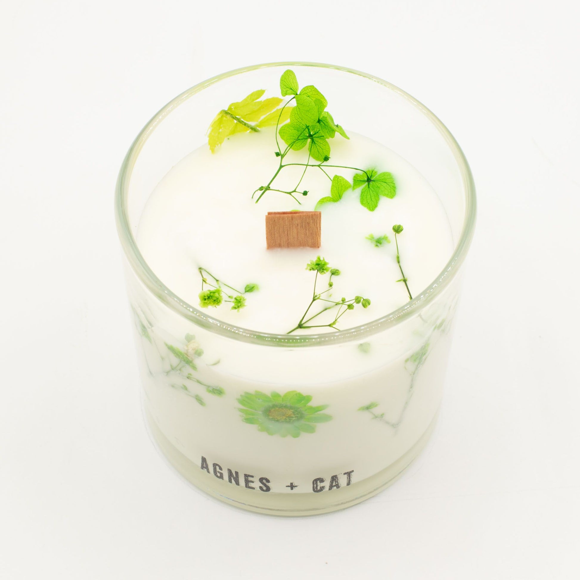 Agnes + Cat Fellberry botanical soy wax candle by The Bliss Co, showcasing a white candle with floral design and wooden wick.