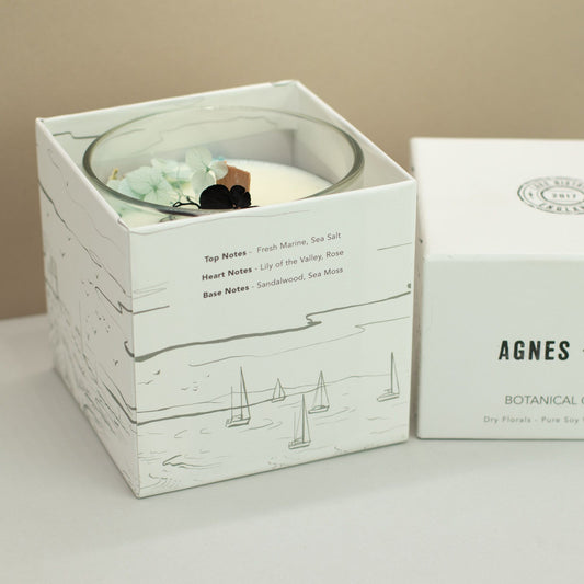 Agnes + Cat Botanical Soy Wax Candle by The Bliss Co in seasalt and moss scent, with a white ceramic holder and natural botanical accents